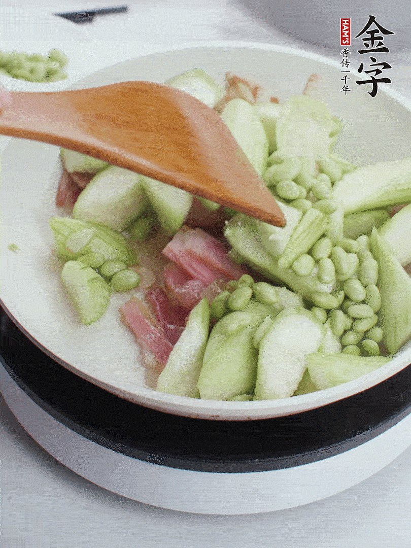 依次下絲瓜、青豆翻炒，炒至絲瓜打蔫縮小。