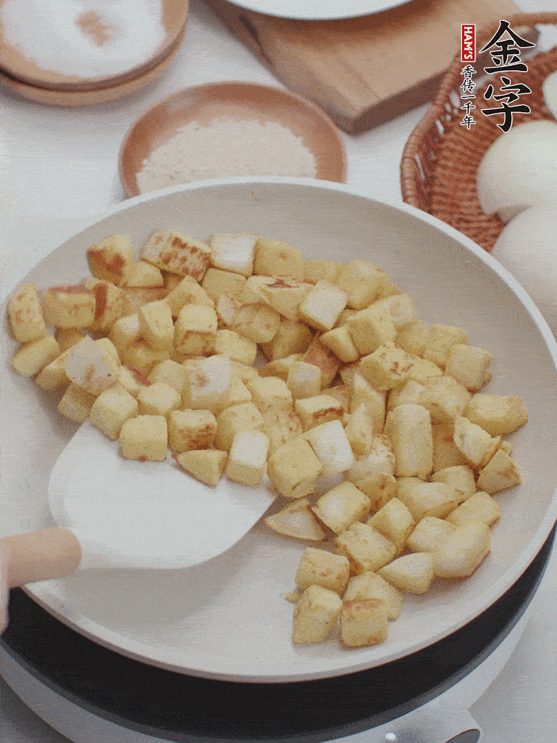 起鍋熱油，倒入饅頭丁，小火煎至蛋液凝固定型再翻面，饅頭丁部煎至金黃時(shí)盛起待用。