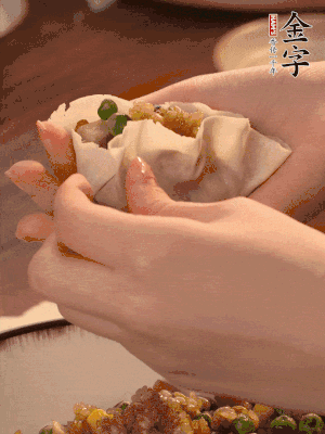 取一大勺餡料放進(jìn)餃子皮里，用大拇指按住頂部餡料，再用虎口掐出形狀。